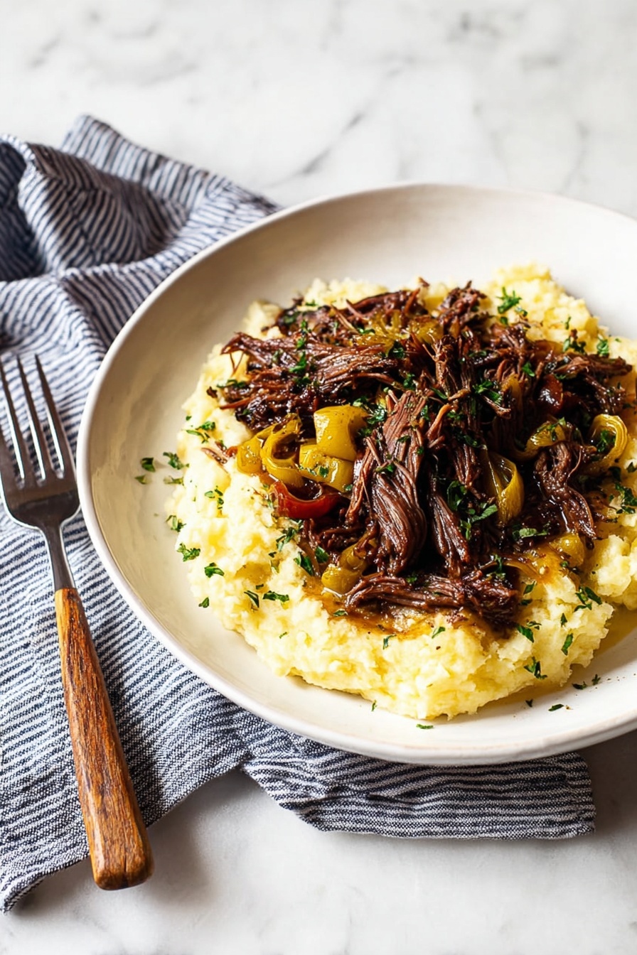 Mississippi Pot Roast - A white plate sits on a neatly folded blue and white striped cloth with a wooden-handled fork beside it, all placed on a white marbled surface. The plate holds two layers: the bottom layer is a creamy, light yellow mashed potato slightly textured and fluffy, while the top layer consists of dark brown, tender, shredded meat pieces mixed with small yellow roasted peppers, garnished with finely chopped green herbs scattered lightly over the dish. The lighting highlights the textures and colors, making the food look warm and inviting. Photo taken with an iphone --ar 2:3 --v 7