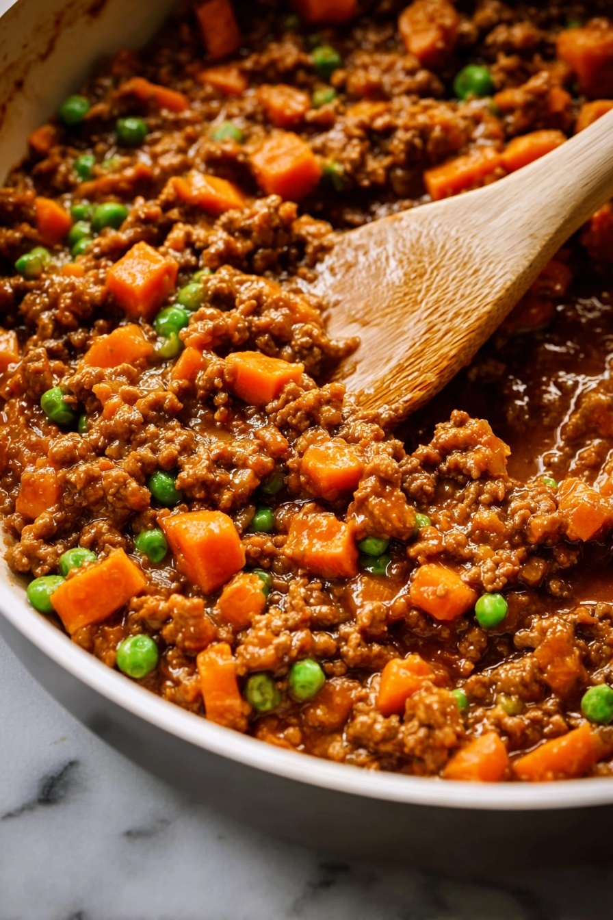 A close-up of a cooked mixture in a pan, showing three main layers: small brown meat pieces spread evenly, bright orange carrot chunks scattered throughout, and small green peas placed randomly on top. The texture looks moist with a slight shine, and a wooden spoon is stirring the food from the right side, with a visible part of a woman's hand holding it. The pan is white, and the setting is on a white marbled surface. photo taken with an iphone --ar 2:3 --v 7