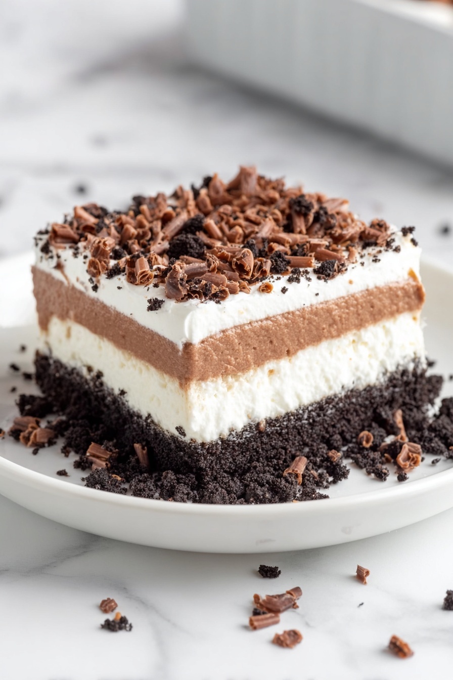 A square dessert with four visible layers sits on a white plate. The bottom layer is dark and crumbly, resembling crushed cookies. Above it is a thick white cream layer, smooth and fluffy. The third layer is shiny and dark brown, similar to chocolate pudding or mousse. Another white cream layer follows, topped with a thick sprinkle of dark cookie crumbs. On top, there are many small, curly chocolate shavings scattered around the surface and plate. The plate rests on a white marbled background, with soft natural light highlighting the dessert's texture and layers. photo taken with an iphone --ar 2:3 --v 7