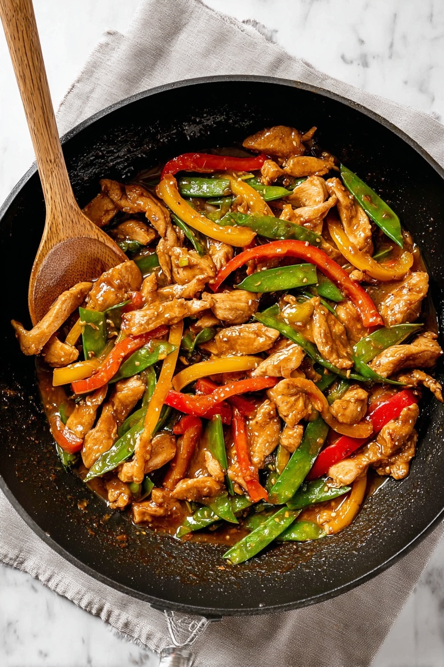 The image shows a black pan filled with a stir fry. The dish has three main layers: at the bottom is a sauce with a shiny brown color covering the pan, the middle layer has sliced pieces of cooked chicken with a light brown, slightly glossy texture, and the top layer includes green snap peas, bright red bell pepper strips, and yellow bell pepper strips scattered evenly throughout. A wooden spoon is lifting some of the stir fry on the left side. The pan is resting on a light gray cloth on a white marbled surface. Photo taken with an iphone --ar 2:3 --v 7