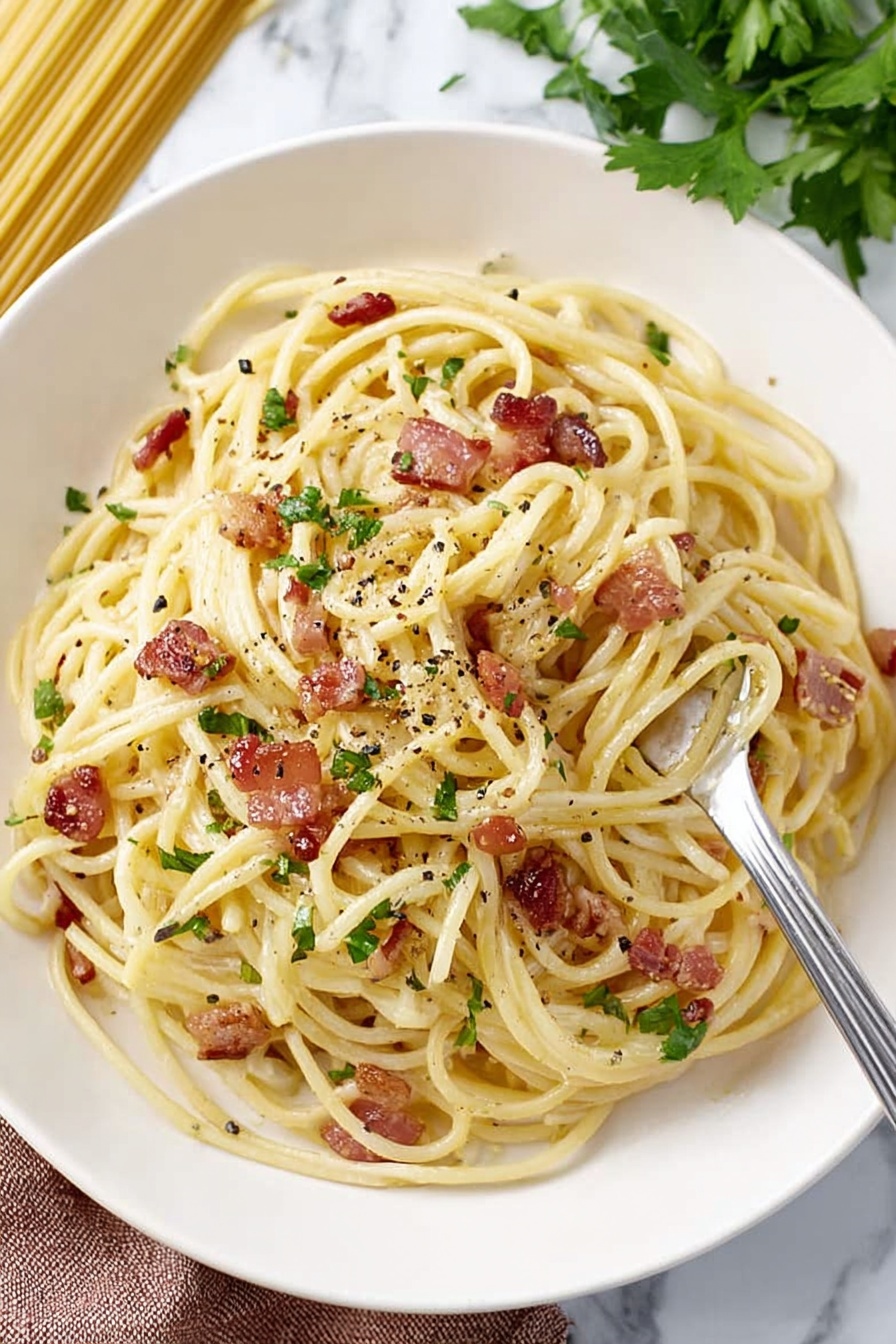 A white plate holds a serving of spaghetti pasta with light yellow strands twisted together, mixed with small pieces of crispy brown bacon scattered throughout. Bits of green herbs are sprinkled evenly on top, adding fresh color. Small black pepper flakes are visible on the pasta, giving a textured look. A silver fork on the right side twirls some spaghetti with a piece of bacon on it. The background is a white marbled surface with some green parsley leaves in the top right corner and uncooked pasta strands slightly blurred in the background photo taken with an iphone --ar 2:3 --v 7