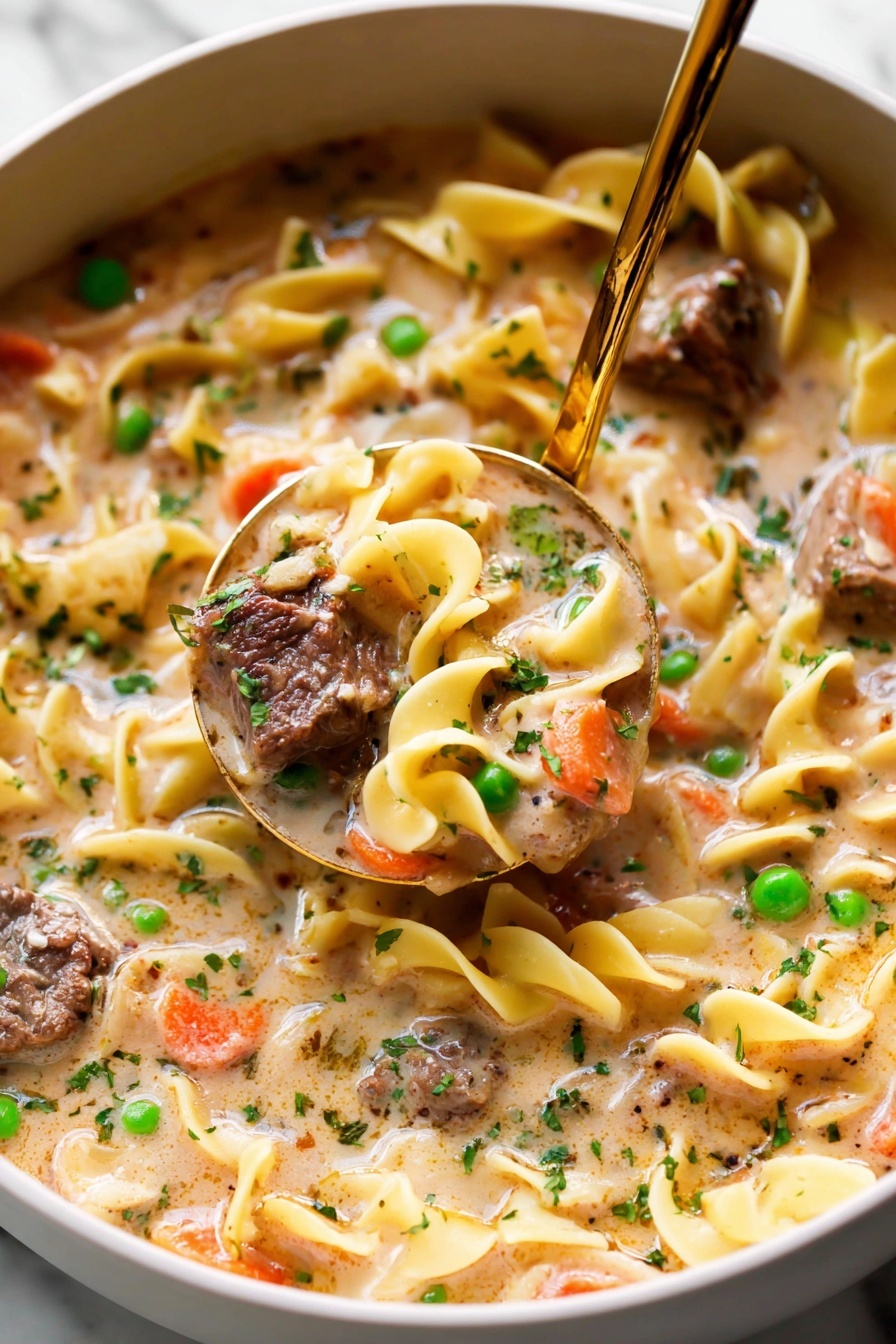 The image shows a bowl filled with thick soup that has three main visible layers: large yellowish egg noodles with a smooth, slightly curled texture, browned chunks of meat with a coarse surface, and bright green peas with smooth skins. There are also small pieces of orange carrots scattered throughout. The soup liquid is creamy light brown, coating all ingredients evenly. Small specks of fresh parsley are sprinkled on top and throughout, adding green bursts of color. The bowl is white with tiny brown spots and sits on a white marbled texture. A silver spoon is partially inside the bowl. Photo taken with an iphone --ar 2:3 --v 7