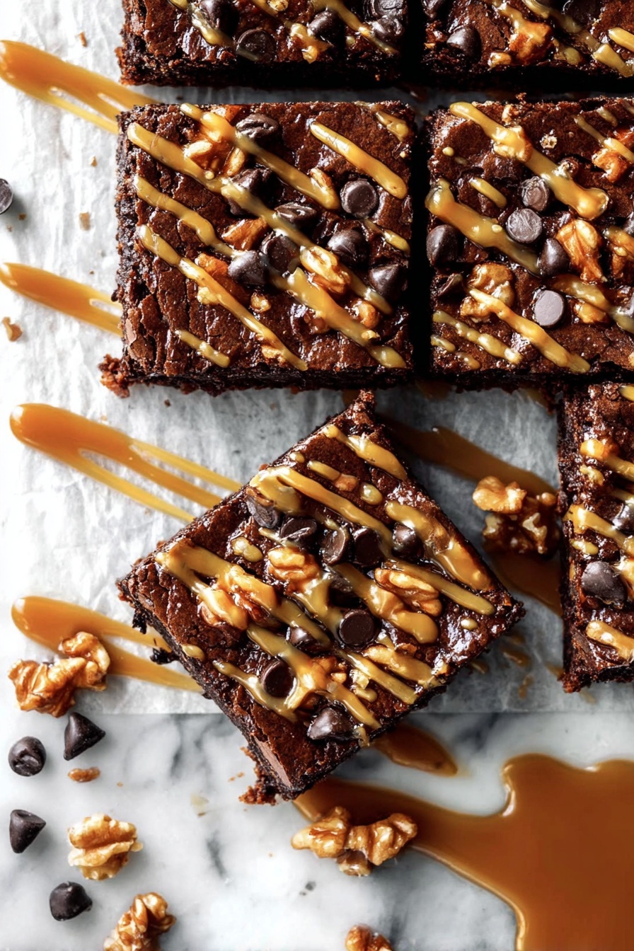 The image shows a close-up of a square chocolate brownie cut into smaller squares. Each piece has a shiny, dark brown top layer with a rich texture, covered with scattered walnuts and chocolate chips. A golden caramel sauce drizzled in thin lines crosses each brownie piece, adding a shiny contrast to the dark chocolate. There is parchment paper under the brownies, and extra caramel sauce is spilled near the right side on the white marbled surface. Some loose chocolate chips and walnut pieces are scattered around the brownies. Photo taken with an iphone --ar 2:3 --v 7