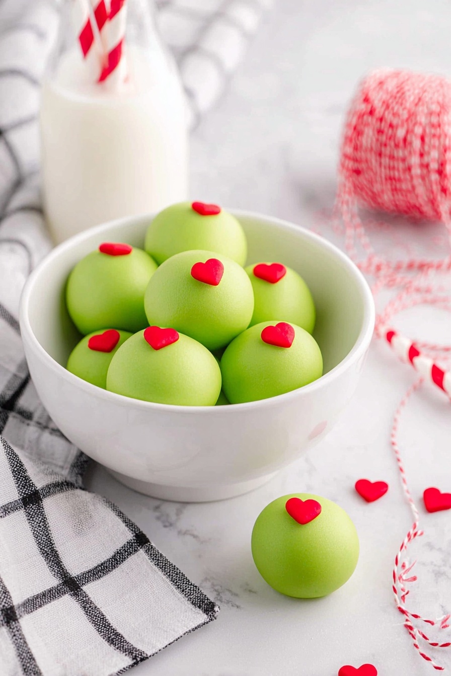 A white bowl filled with seven round, smooth, light green treats, each topped with a small red heart decoration on the top center; one of these treats sits outside the bowl on a white marbled surface next to a black and white checkered cloth. Behind the bowl, there is a small glass bottle filled with milk with two red and white striped paper straws inside. To the right, a red and white striped string lies coiled with small red heart decorations scattered nearby. The whole scene is set on a white marbled texture background, giving a clean and bright look. photo taken with an iphone --ar 2:3 --v 7
