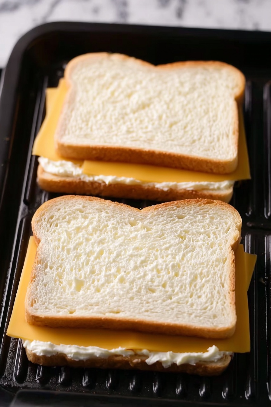Two slices of toasted bread are on white plates, placed on a white marbled surface with a white cloth beneath them. Each slice is covered with a layer of melted cheese that is golden yellow with browned spots evenly spread across the top. The toast has a light brown crust, and the texture of the bread looks crisp yet soft underneath the cheese. The front toast is in clear focus while the second slice on the other plate is slightly blurred in the background, creating depth in the image. photo taken with an iphone --ar 2:3 --v 7