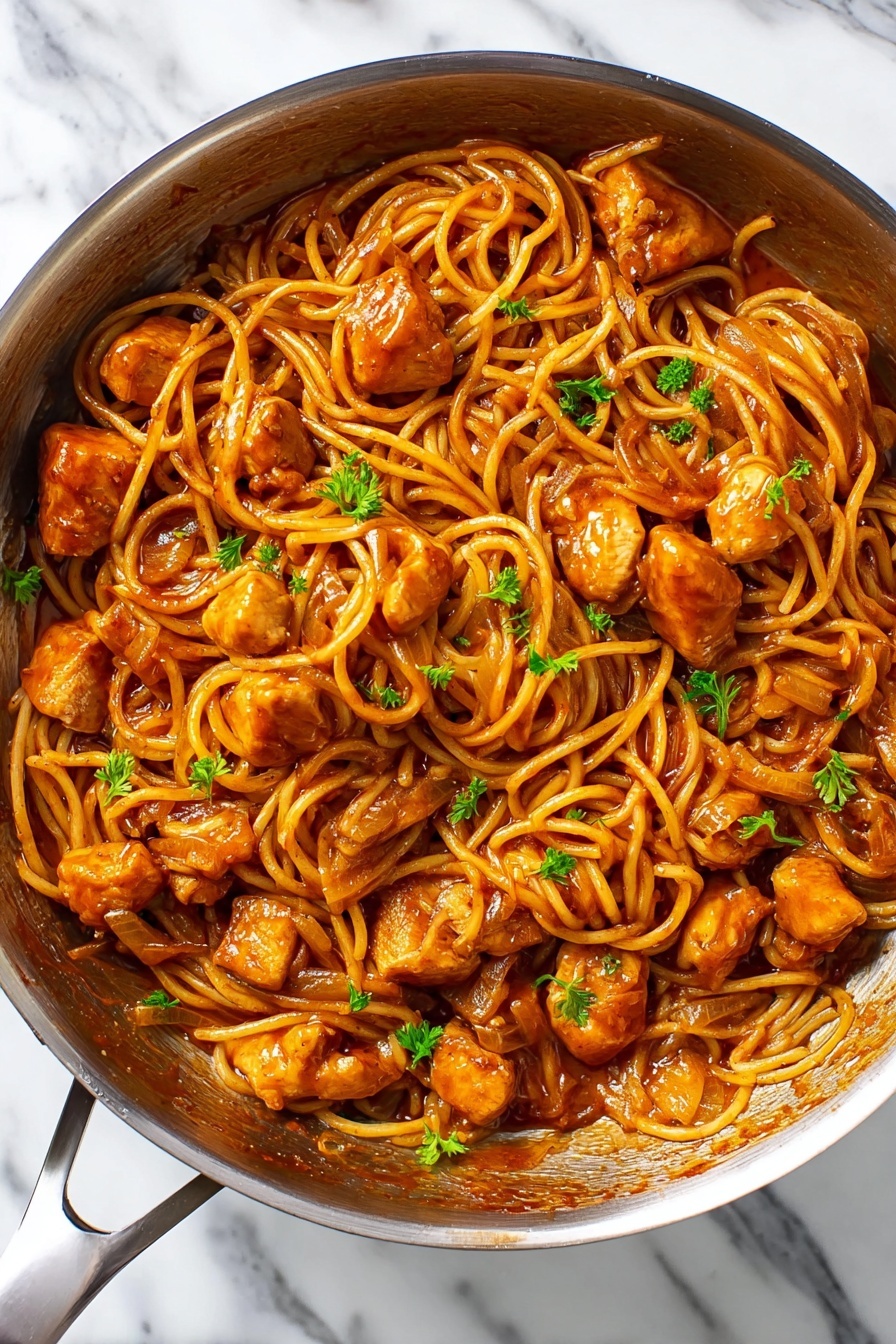 A pan filled with a mix of spaghetti noodles and medium-sized pieces of golden-brown chicken, all coated in a thick reddish-brown sauce. The spaghetti noodles are layered loosely, swirling around and partly tangled with the chicken pieces. There are some bits of cooked onion visible in the sauce, and small green parsley leaves are scattered on top, adding a fresh touch. The pan is silver and sits on a white marbled surface. photo taken with an iphone --ar 2:3 --v 7