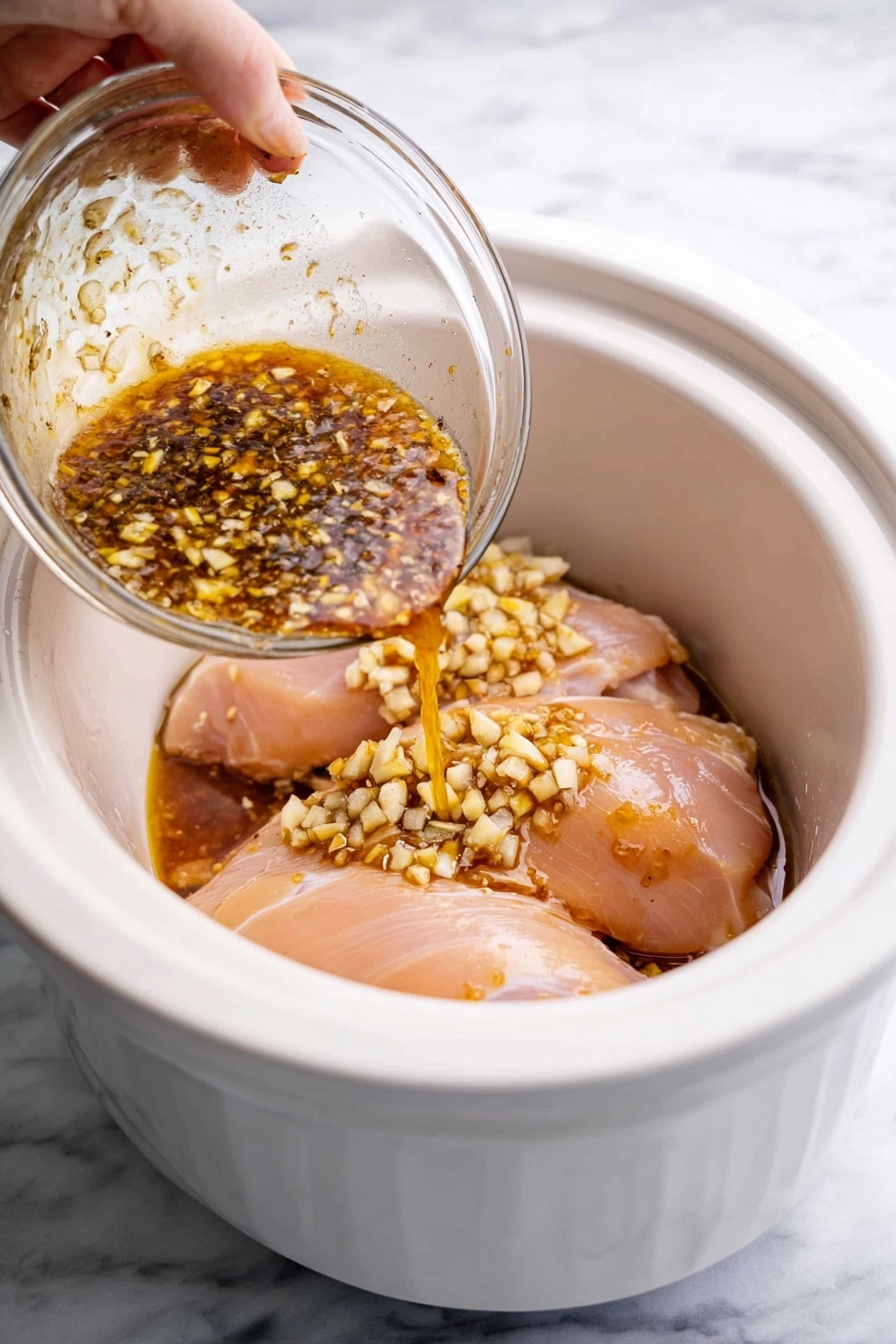 A white bowl with one layer of white cooked rice at the bottom, topped with a thick layer of shredded orange-brown chicken covered in a glossy sauce. The chicken is sprinkled with small black and white sesame seeds and garnished with bright green chopped spring onions scattered on top. A silver spoon rests inside the bowl, partly under the chicken. The bowl is set on a white marbled surface with small side bowls of green onions and sesame seeds nearby. photo taken with an iphone --ar 2:3 --v 7